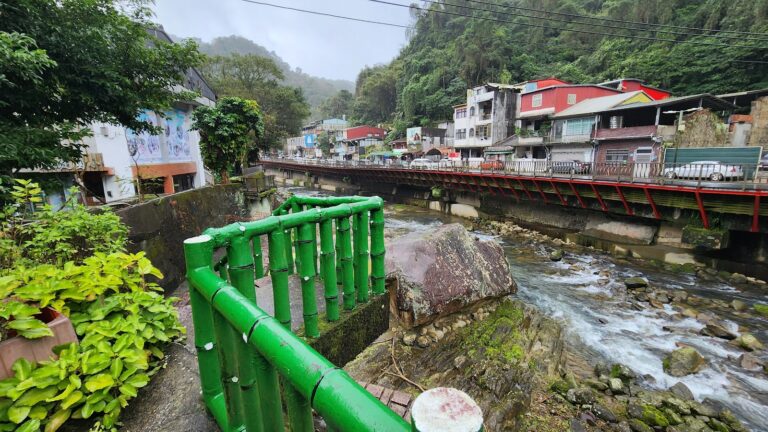 石碇烏塗溪步道吊橋,綠色欄杆與紅色拱橋倒影在清澈溪水中
