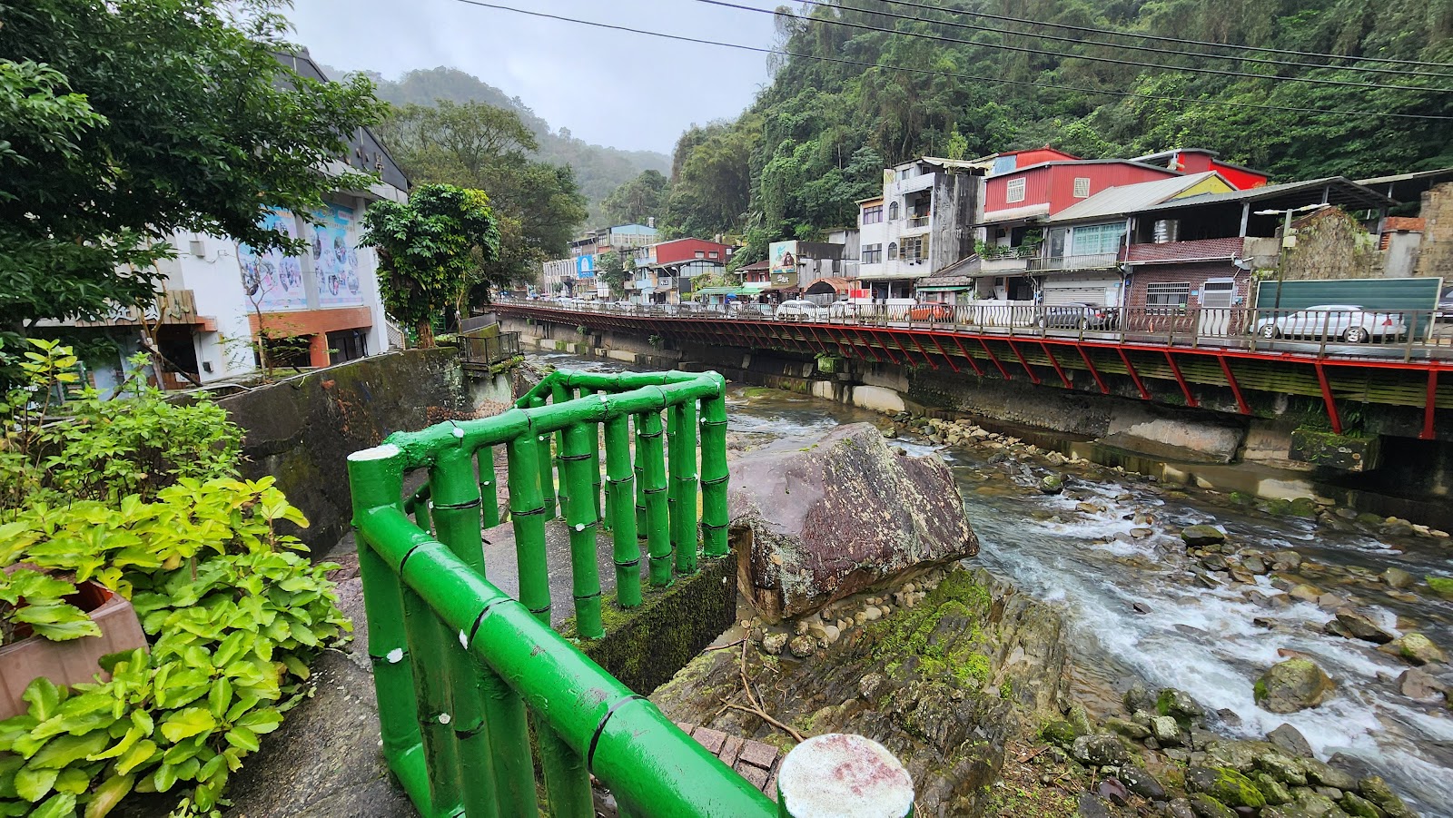 石碇烏塗溪步道吊橋，綠色欄杆與紅色拱橋倒影在清澈溪水中