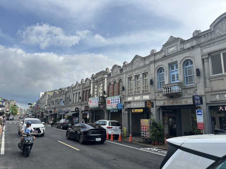 台南新化老街日式巴洛克街屋立面，藍天白雲，機車穿梭