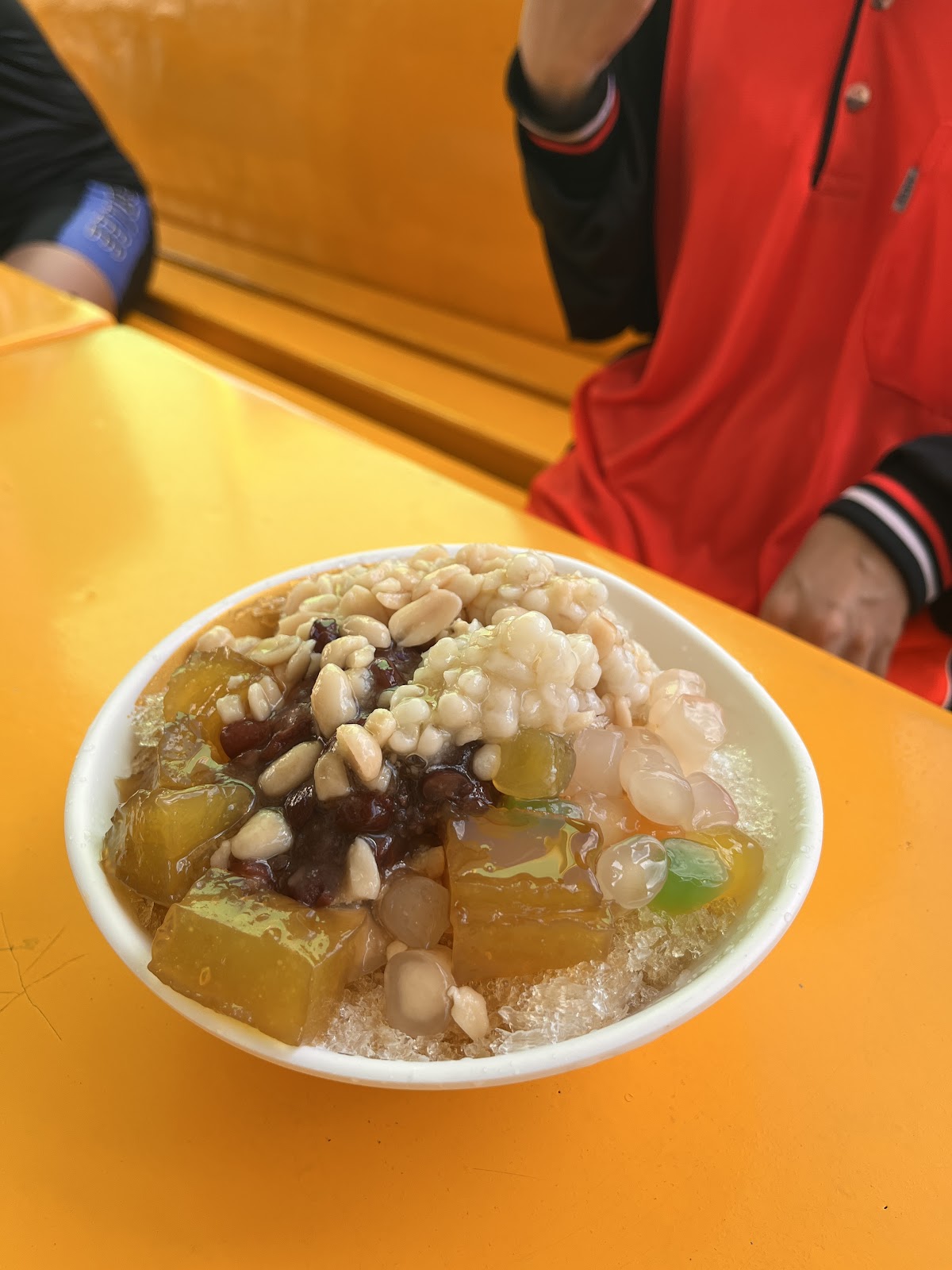 手持一碗招牌豆花冰，配料有紅豆和手工湯圓