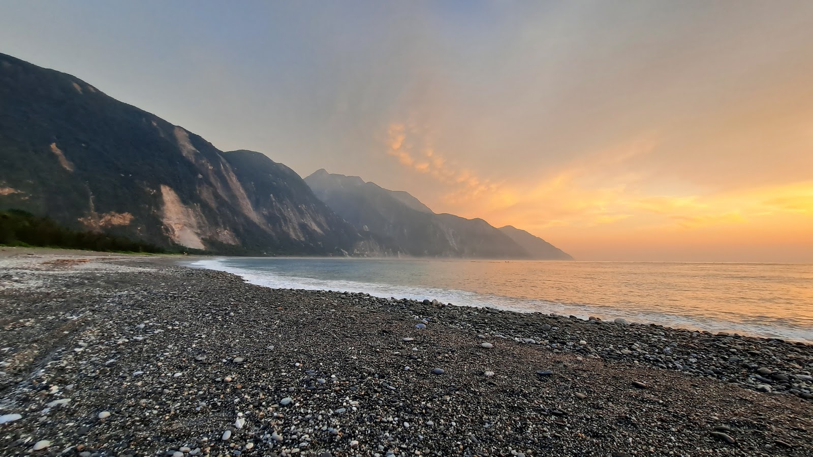 夕照下崇德礫灘與清水斷崖,橘金色天空映照大理石峭壁