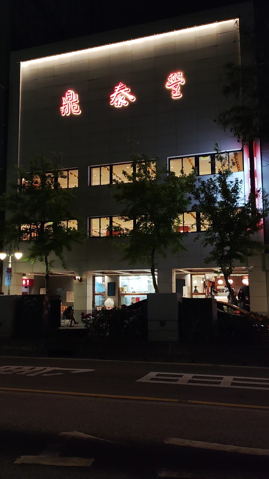 鼎泰豐信義店夜間外觀,灰色建築頂部紅色霓虹招牌