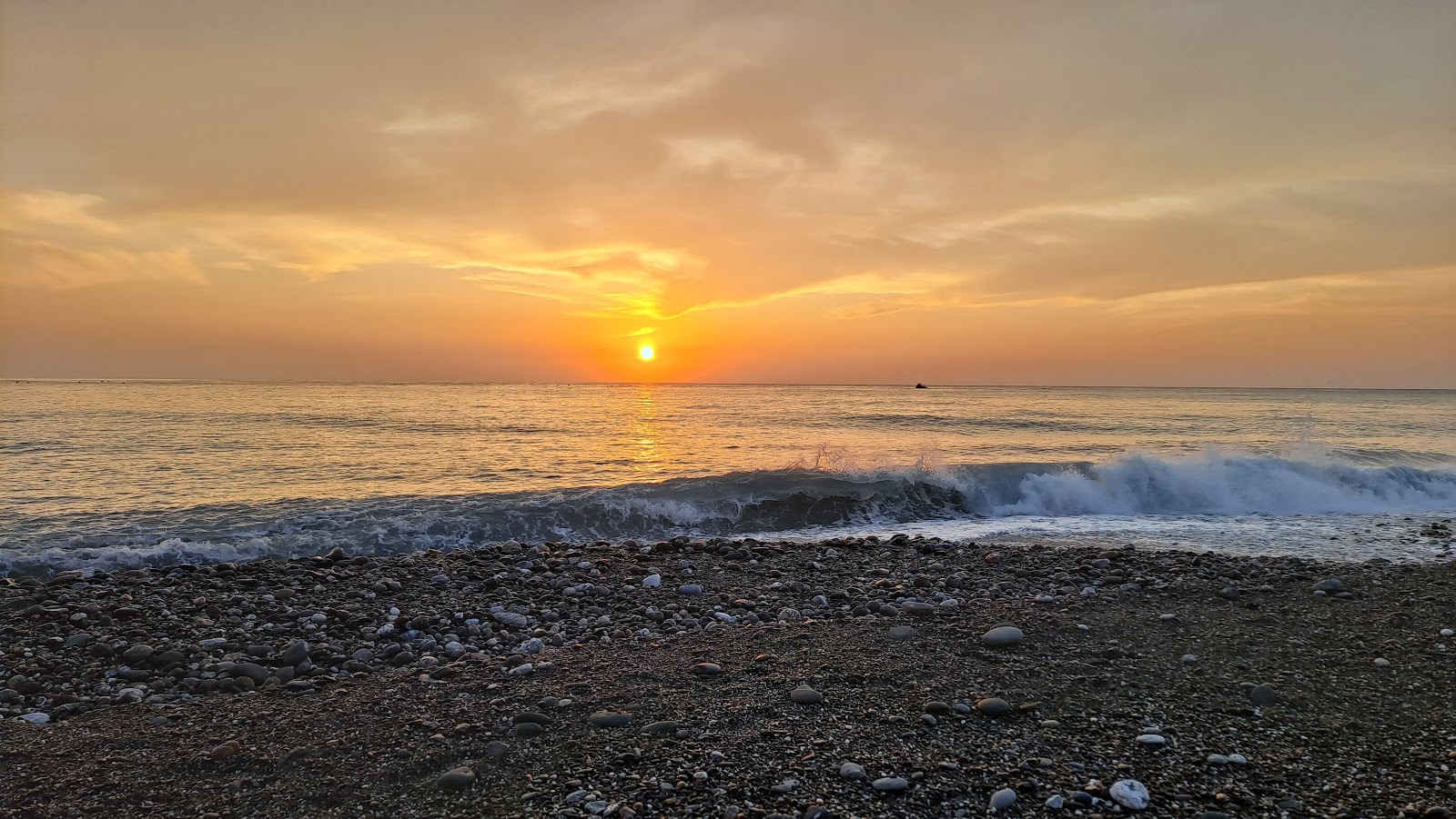 崇德礫石灘夕陽日落,金橘色天空與海浪拍岸