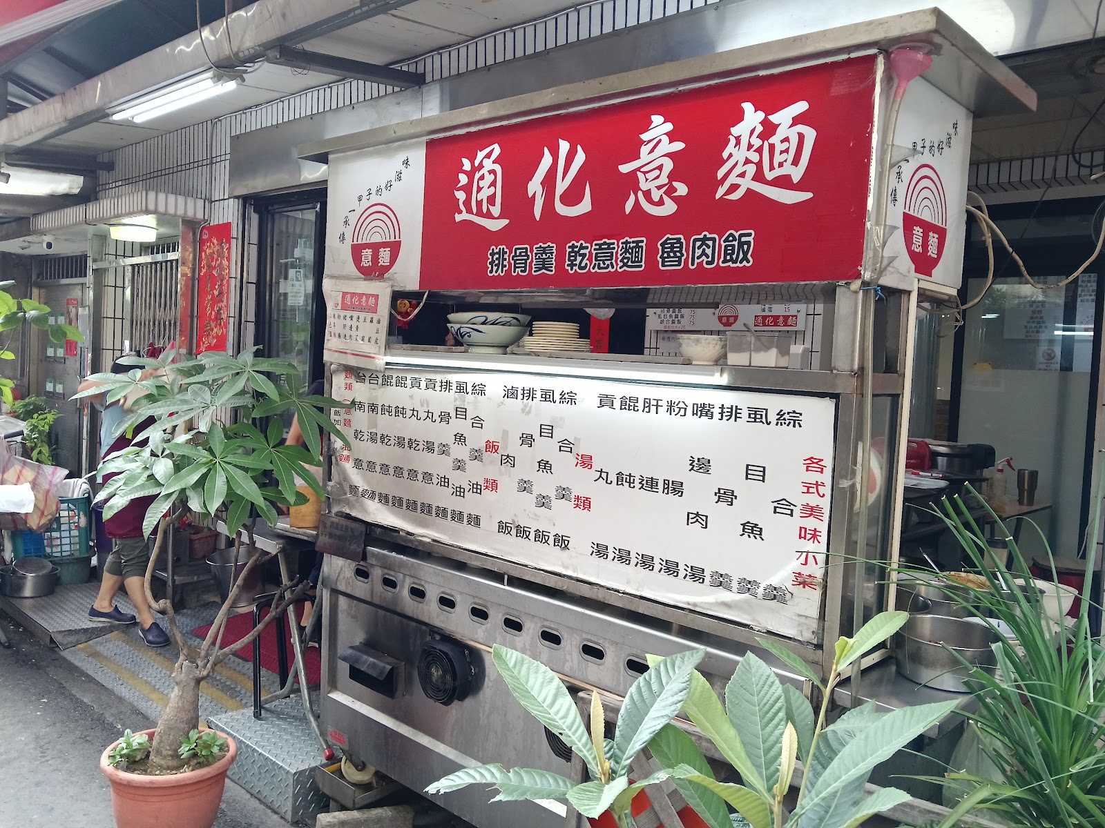通化意麵攤車外觀，紅色招牌寫著排骨羹乾意麵魯肉飯，店門口盆栽點綴