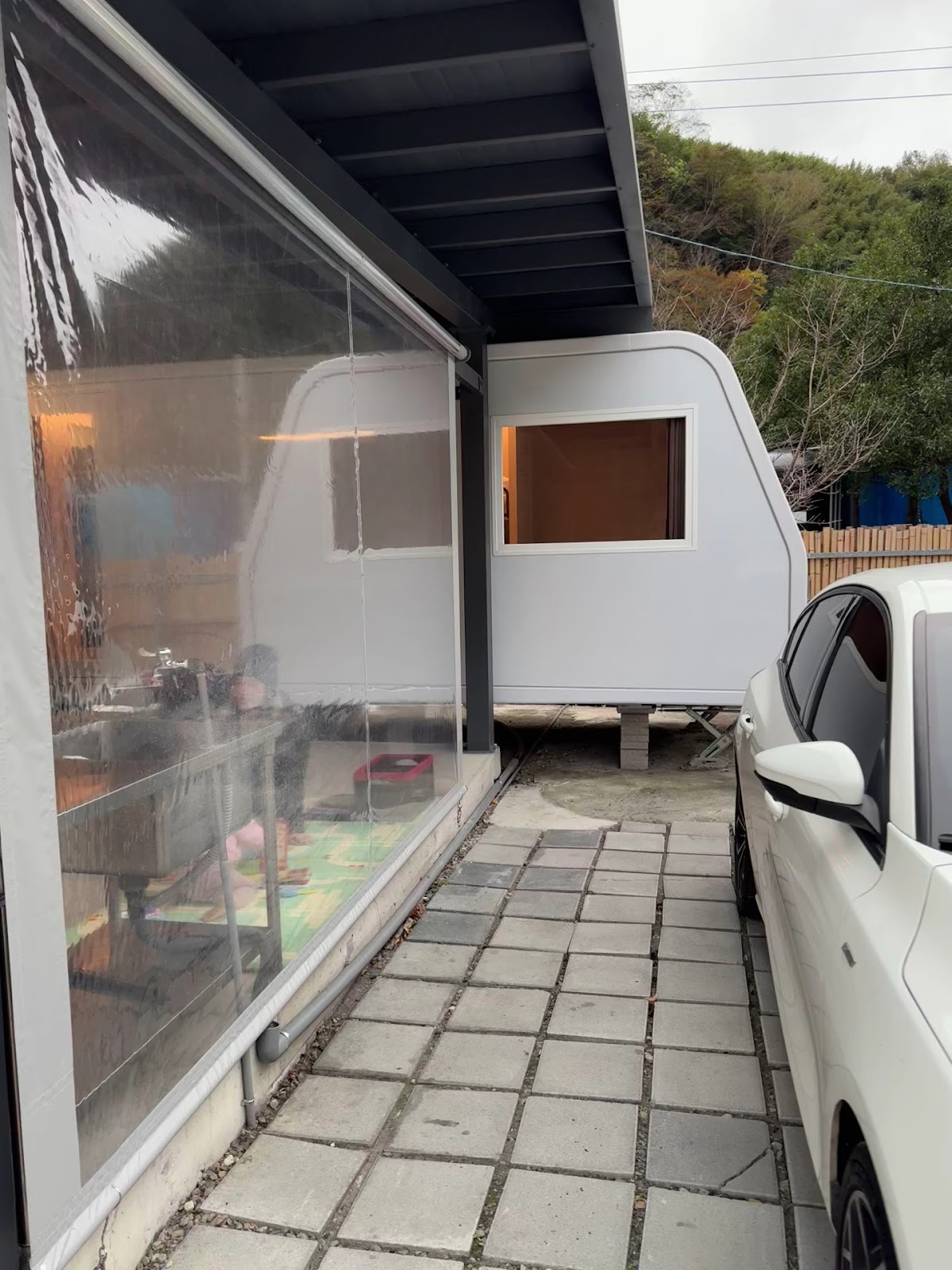 露營拖車停靠雨棚下一旁停著轎車