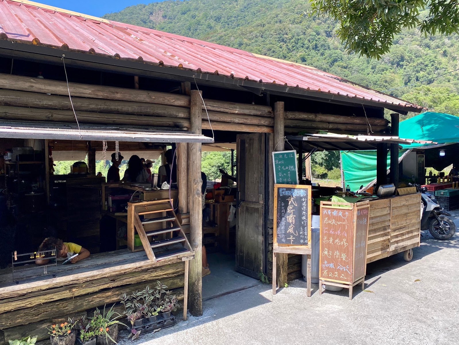 武界壩嵐卡外觀,木造粗獷小屋,紅鐵皮頂,入口旁有黑板菜單,顧客坐在屋內享用餐食