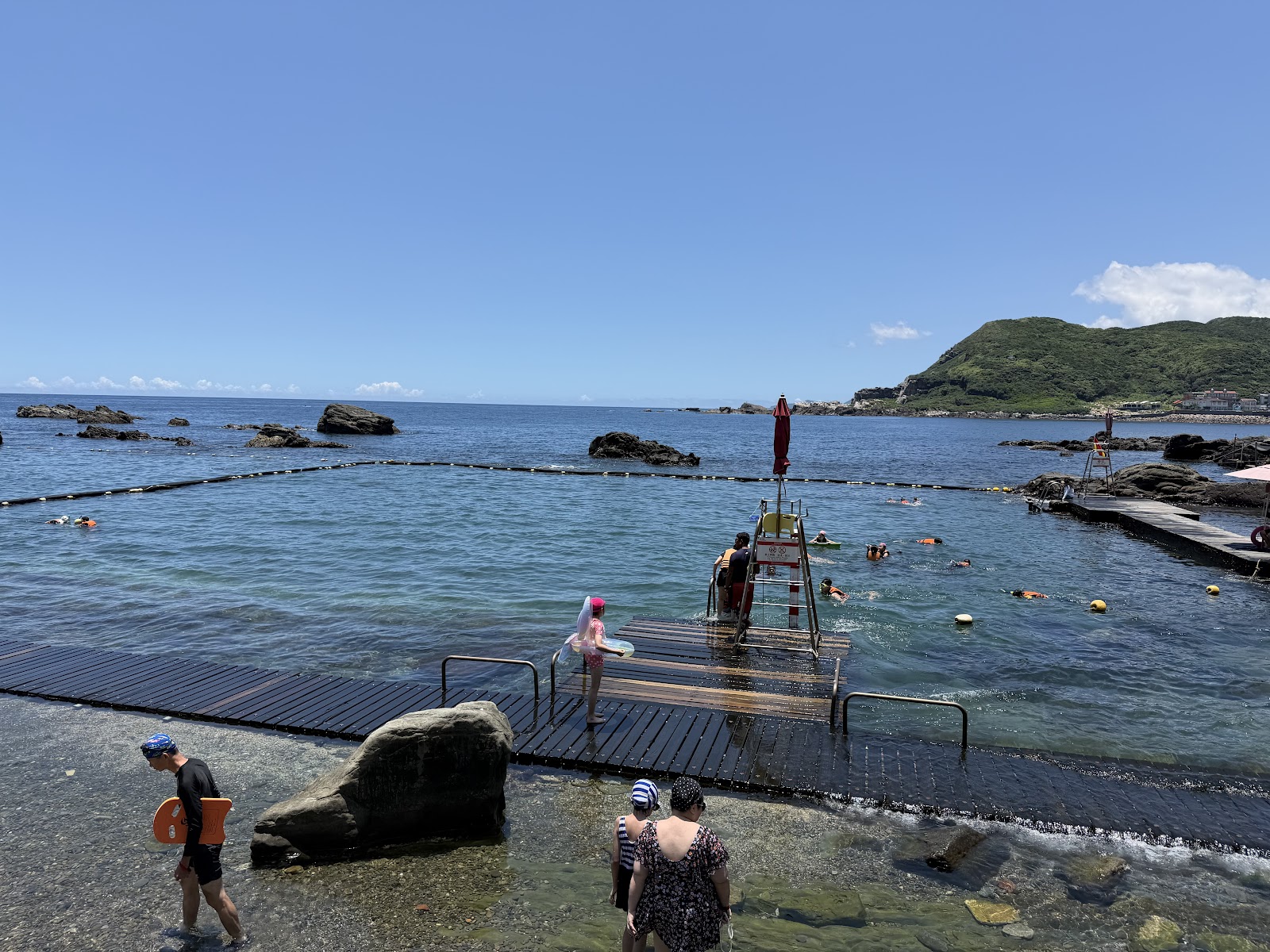 龍洞灣海洋公園開放式海域浮潛區，木棧道下水口，救生員駐守，背景翠綠山丘藍天