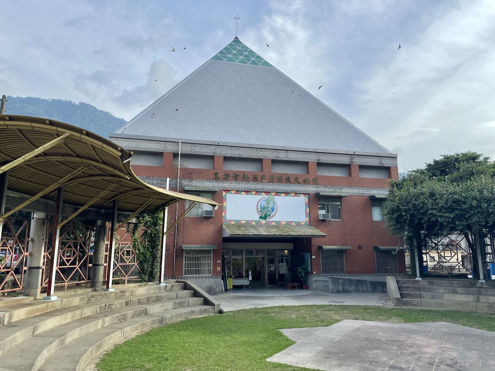 高雄市桃源區原住民文物館外觀,屋頂呈金字塔造型,建築前有弧形看台