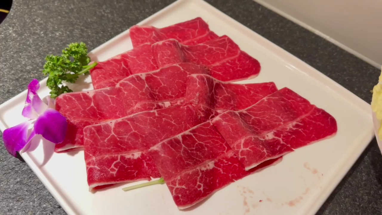 白色盤子上的生牛肉片搭配香草與花朵裝飾