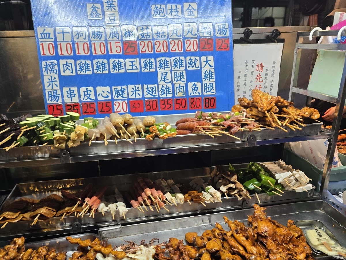旗山烤肉攤位價目表看板，血腸雞腿等多種串烤品項與烤爐