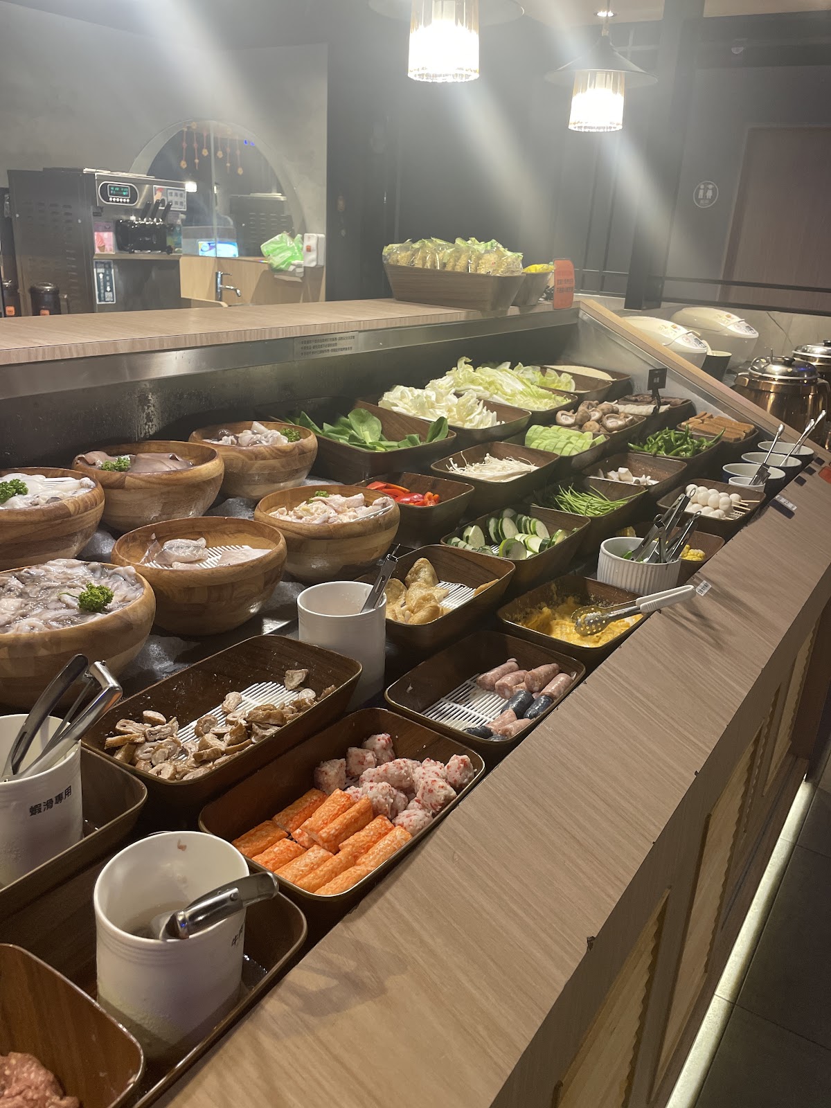 自助式火鍋料理食材檯，木盆盛裝多樣新鮮食材