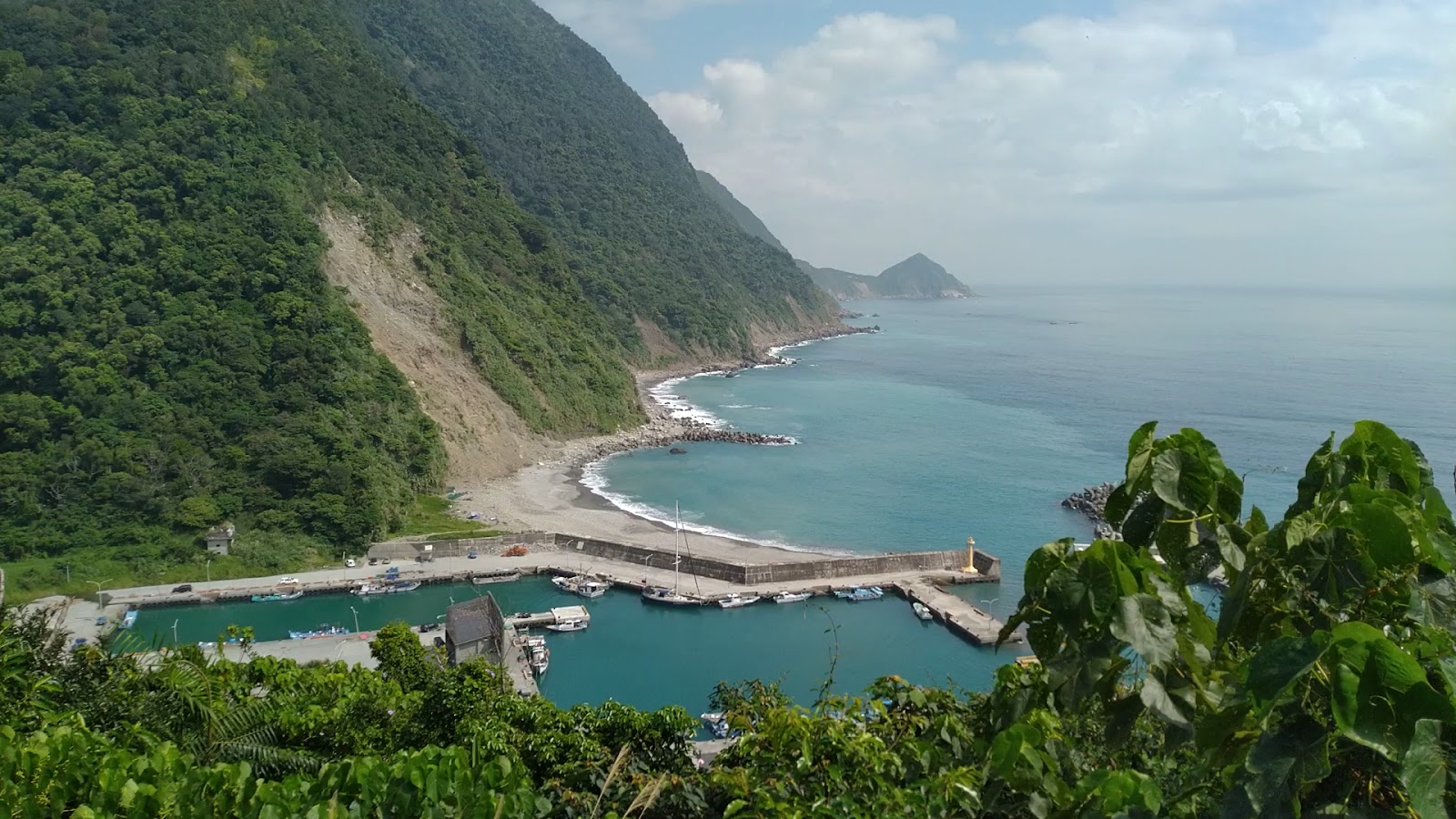 從朝陽步道山頂鳥瞰,小漁港與碧藍弧形海灣,陡峭綠山崖映入眼簾