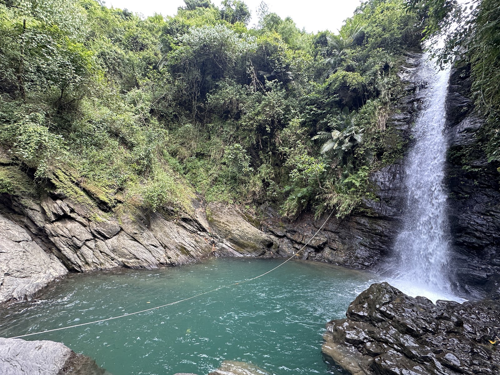 大津瀑布戲水潭全景,瀑布從岩壁右側傾瀉入碧綠潭水