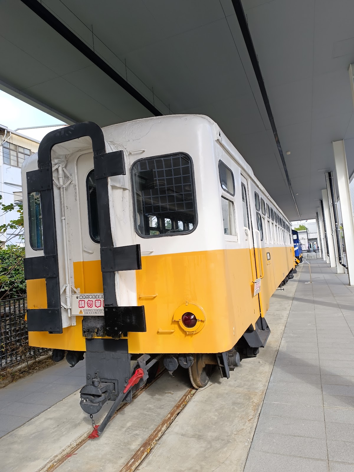 台灣鯛生態創意園區復古黃白色觀光小火車展示車廂，停放於園區遮棚下走道