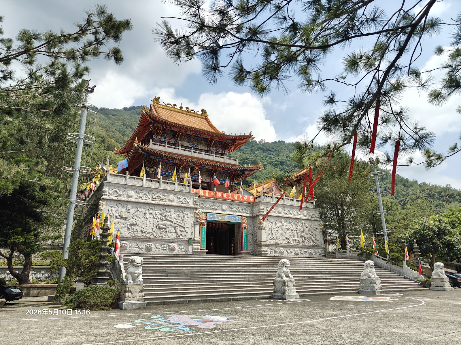 妙通寺殿宇側面，五彩經幡隨風飄揚，山巒環抱更顯靈氣