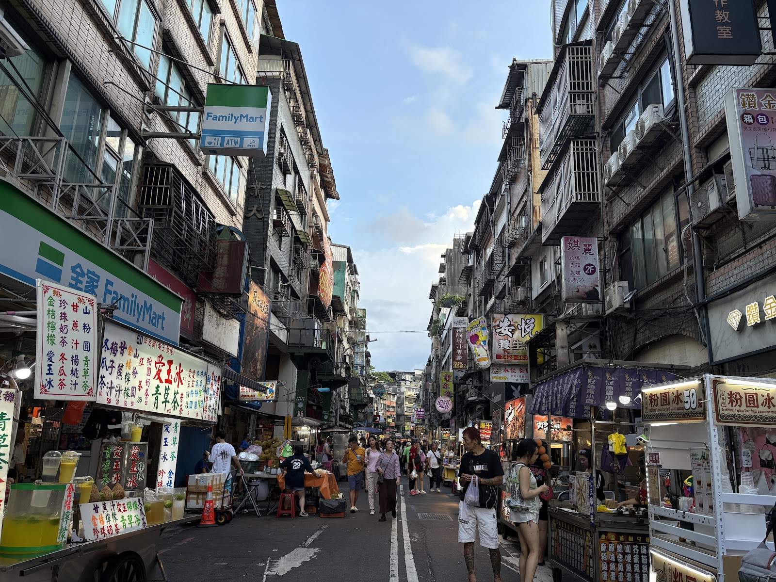 基隆廟口夜市街景，兩側攤販林立，人流不斷，全家便利商店招牌
