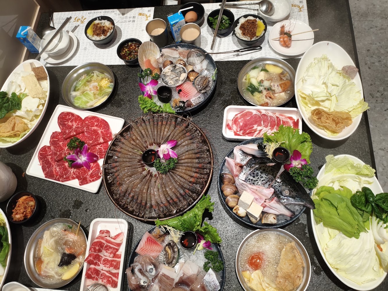 滿桌海鮮牛肉羊肉蔬菜豆腐與大盤生蝦的火鍋餐點