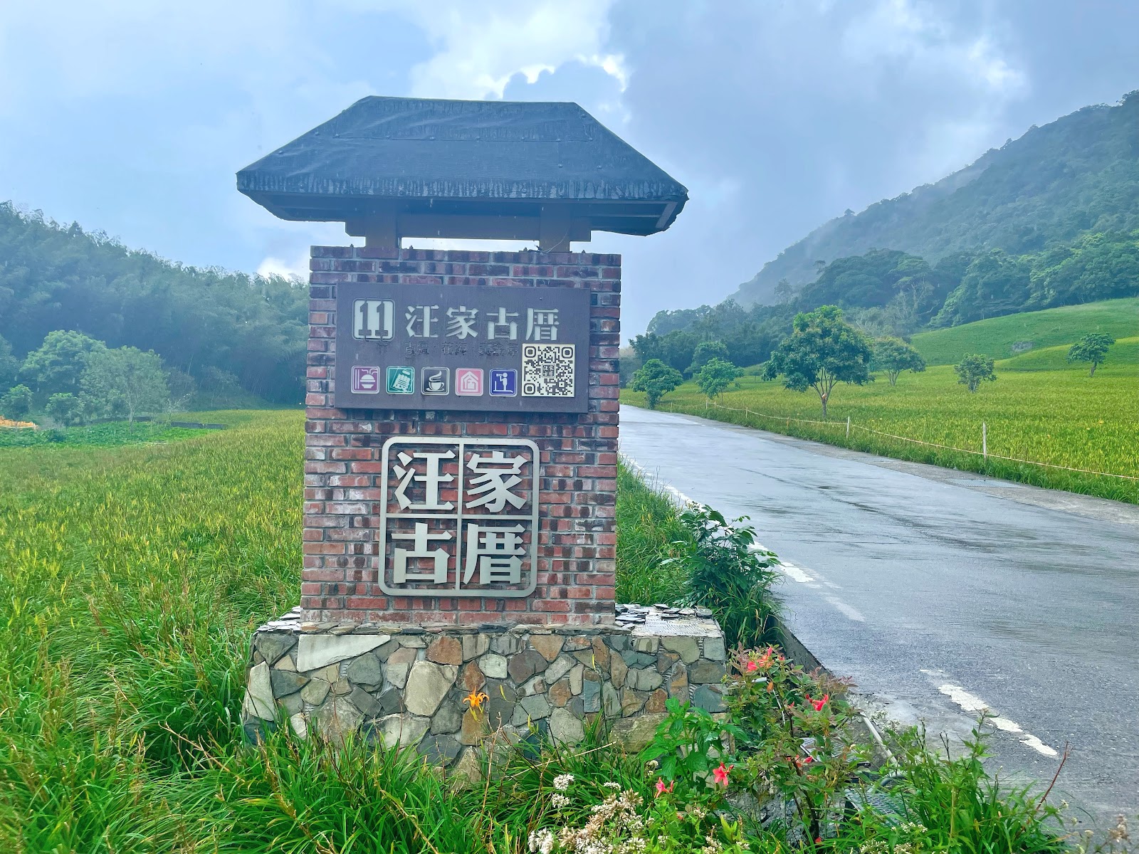 赤科山汪家古厝入口標示,前方稻田翠綠,背靠青山