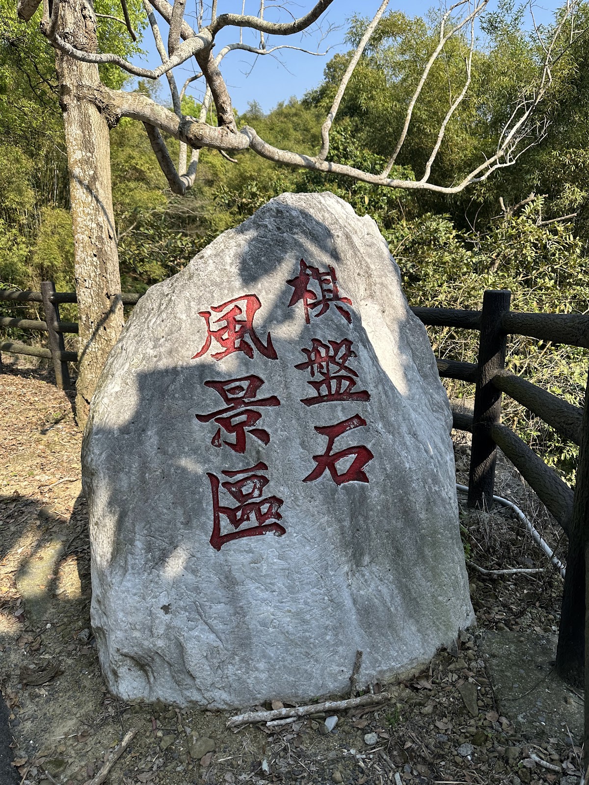 仙洞坪棋盤石風景區石碑特寫，木製欄杆背景，綠意環繞