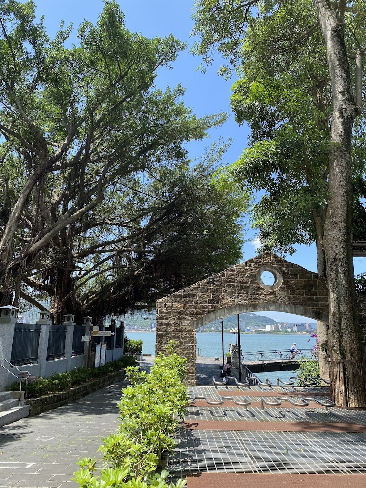 大樹樹蔭步道與石砌拱門眺望河岸山景