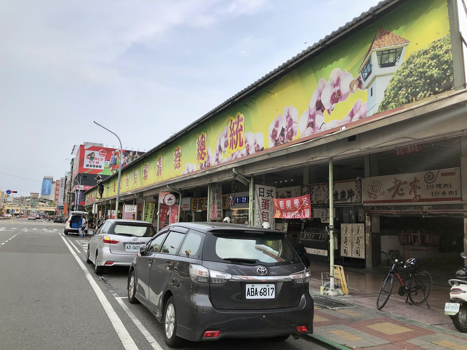 白天市場店面整排景象，招牌林立車輛停放