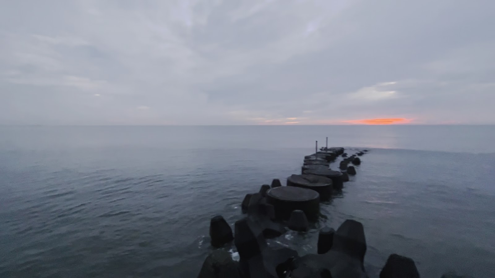 鳳坑漁港消波塊延伸灰色大海,天際橙紅晚霞