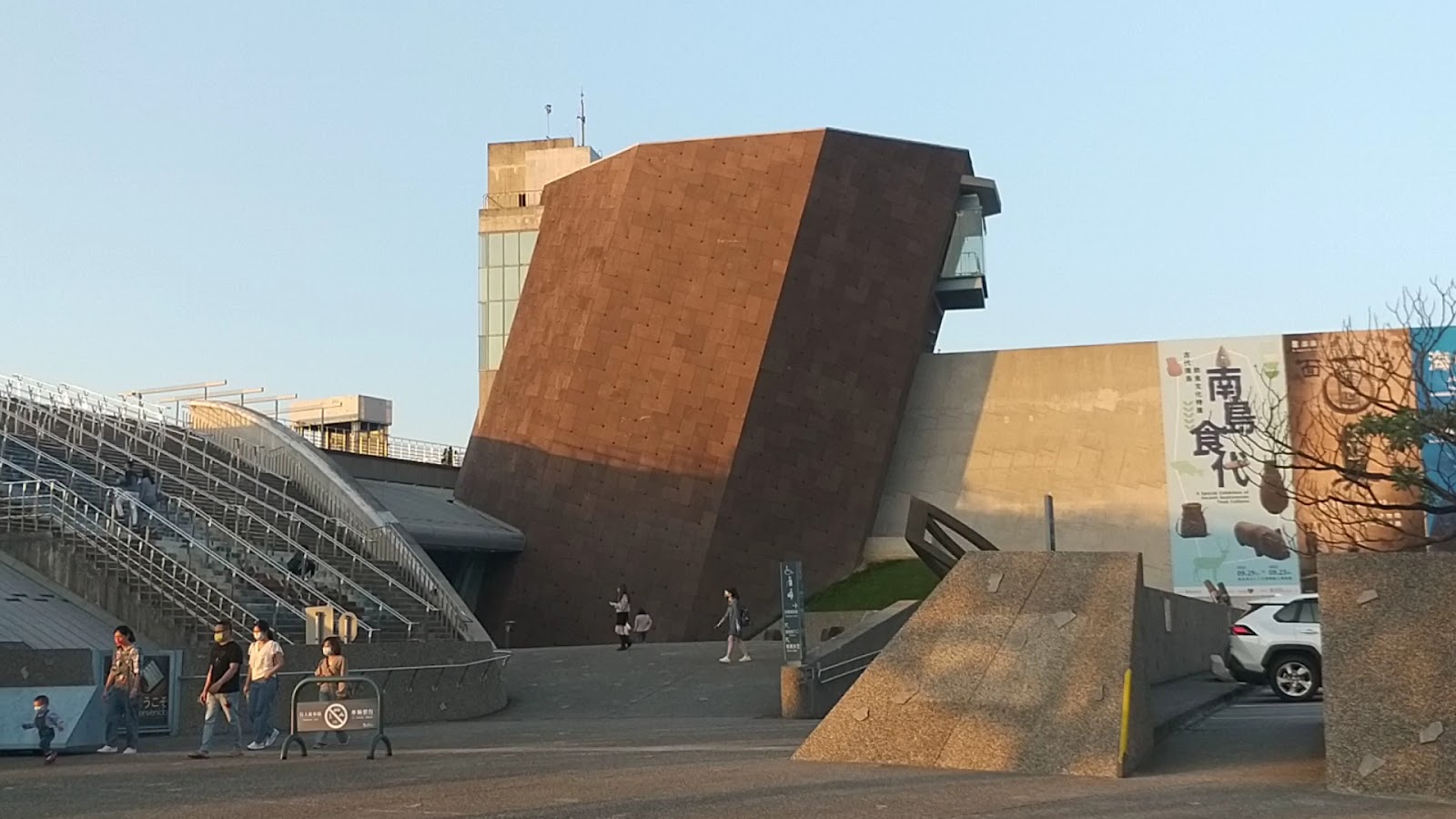 十三行博物館標誌性傾斜磚砌外觀建築,遊客在館外步道行走