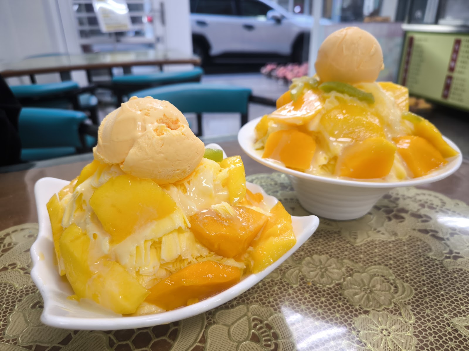玉梅芒果冰店內兩碗芒果冰淇淋，碗中滿是新鮮金黃芒果丁，背景藍色椅子