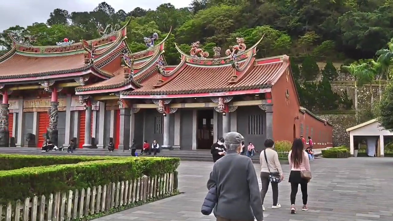 行修宮側面角度，遊客走向廟埕，綠籬環繞