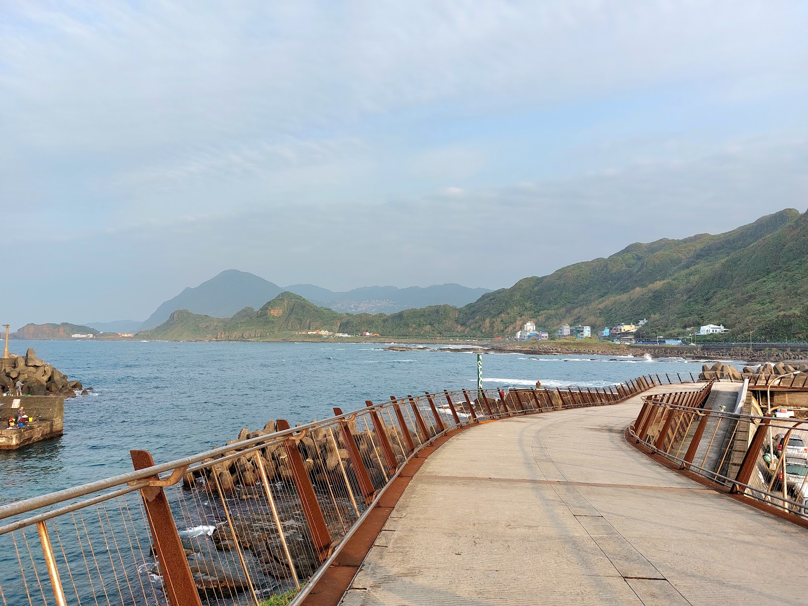望海巷漁港防波堤步道,鏽紅欄杆,蔚藍海面翠綠山丘
