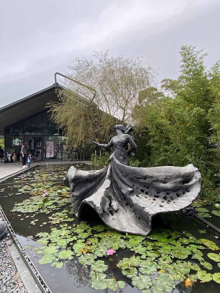蓮花池中的女性舞姿雕塑與現代建築背景