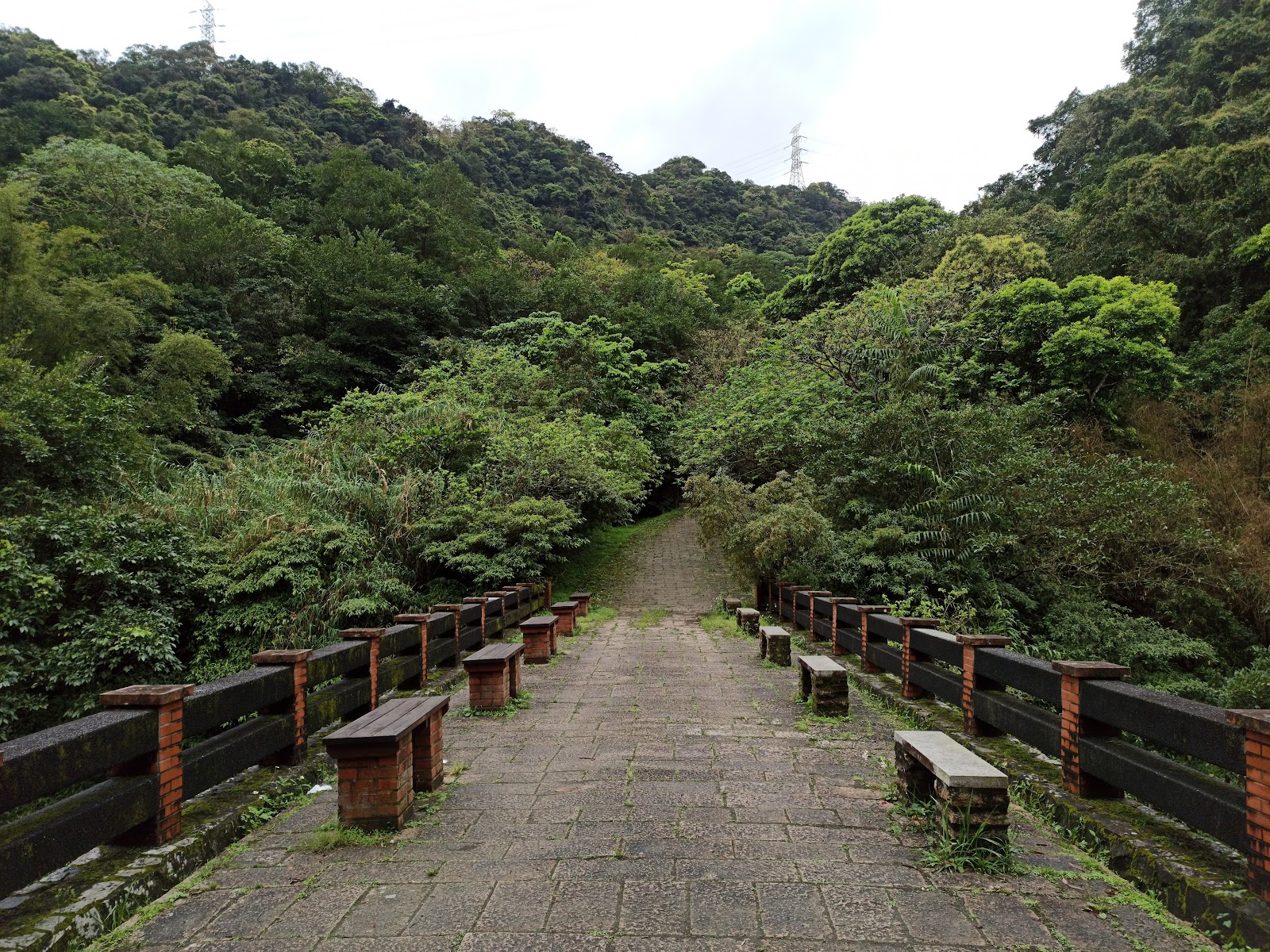 石砌古橋通往山谷,遠方可見高壓電塔