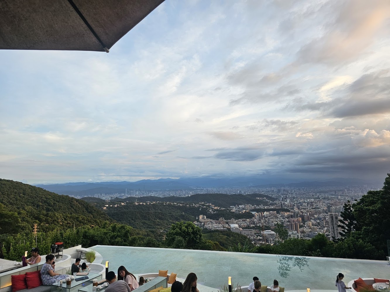 戶外餐廳區前方有無邊際泳池,後方是黃昏山景與城市景色
