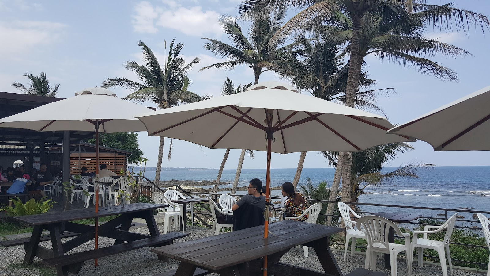 富山漁業資源保育區戶外用餐區，白色遮陽傘下旅客欣賞礁岸海景