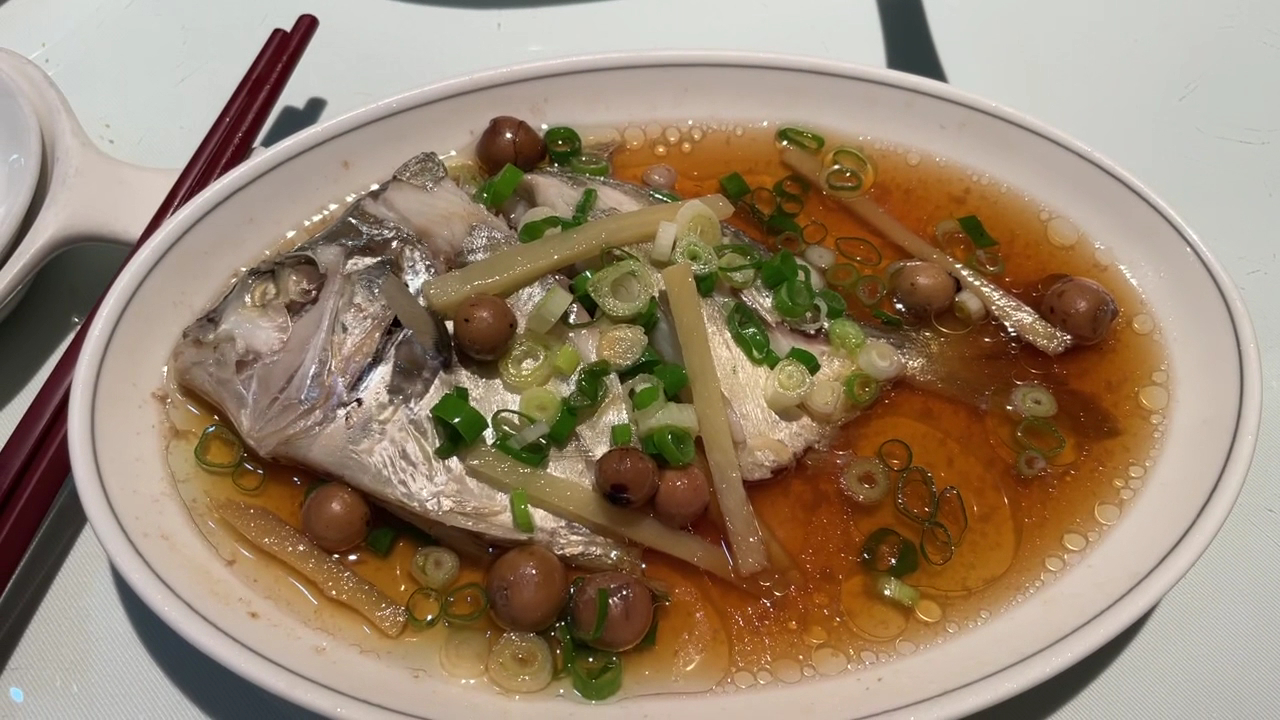 清蒸魚料理,魚上鋪有蔥花、薑絲、醬油及菇類