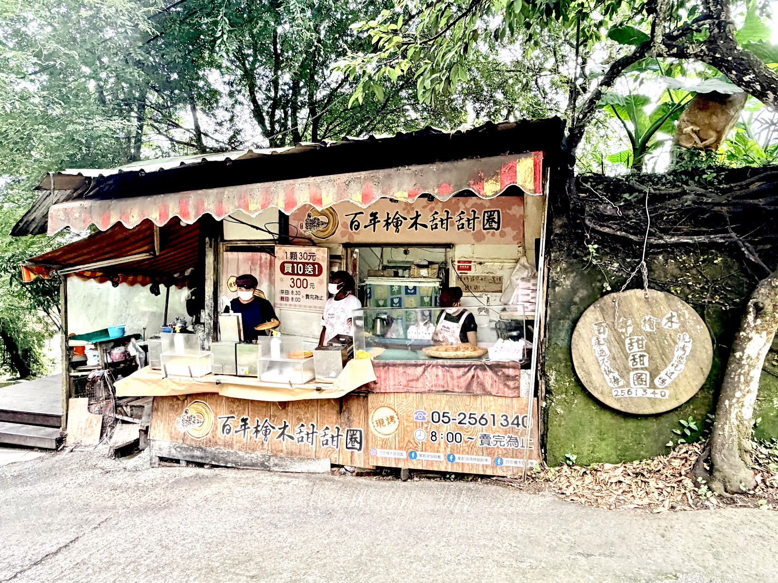 黎明步道花園附近的百年檜木甜甜圈小攤,攤位招牌清晰,旁有大樹遮蔭