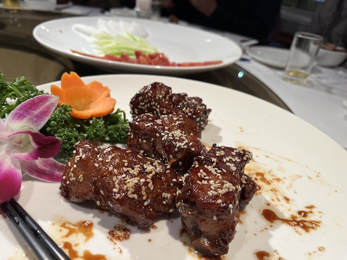 醬燒排骨上灑有白芝麻,附有胡蘿蔔花與蘭花裝飾