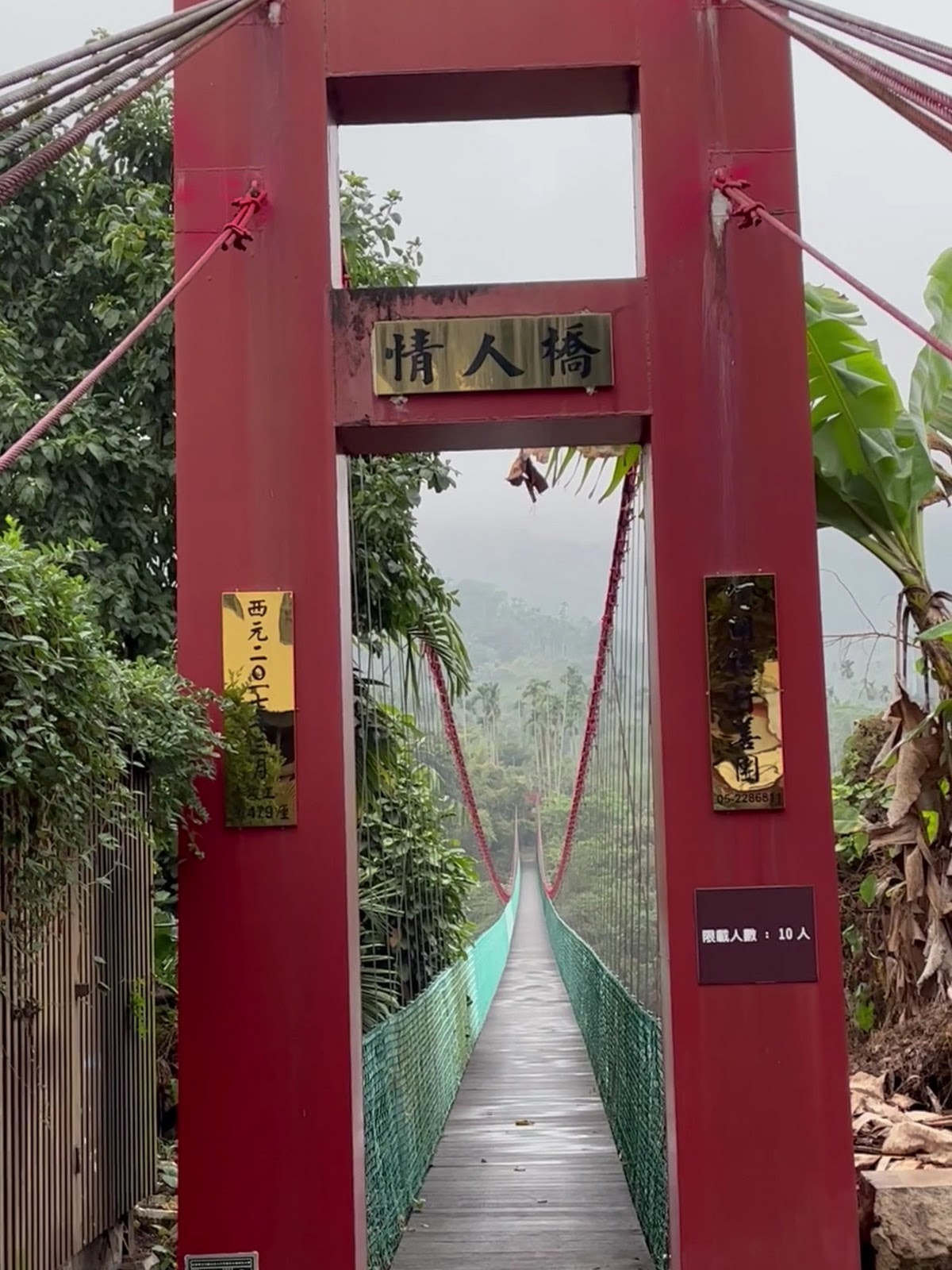 情人橋紅色牌樓入口近拍,吊橋往山林方向延伸