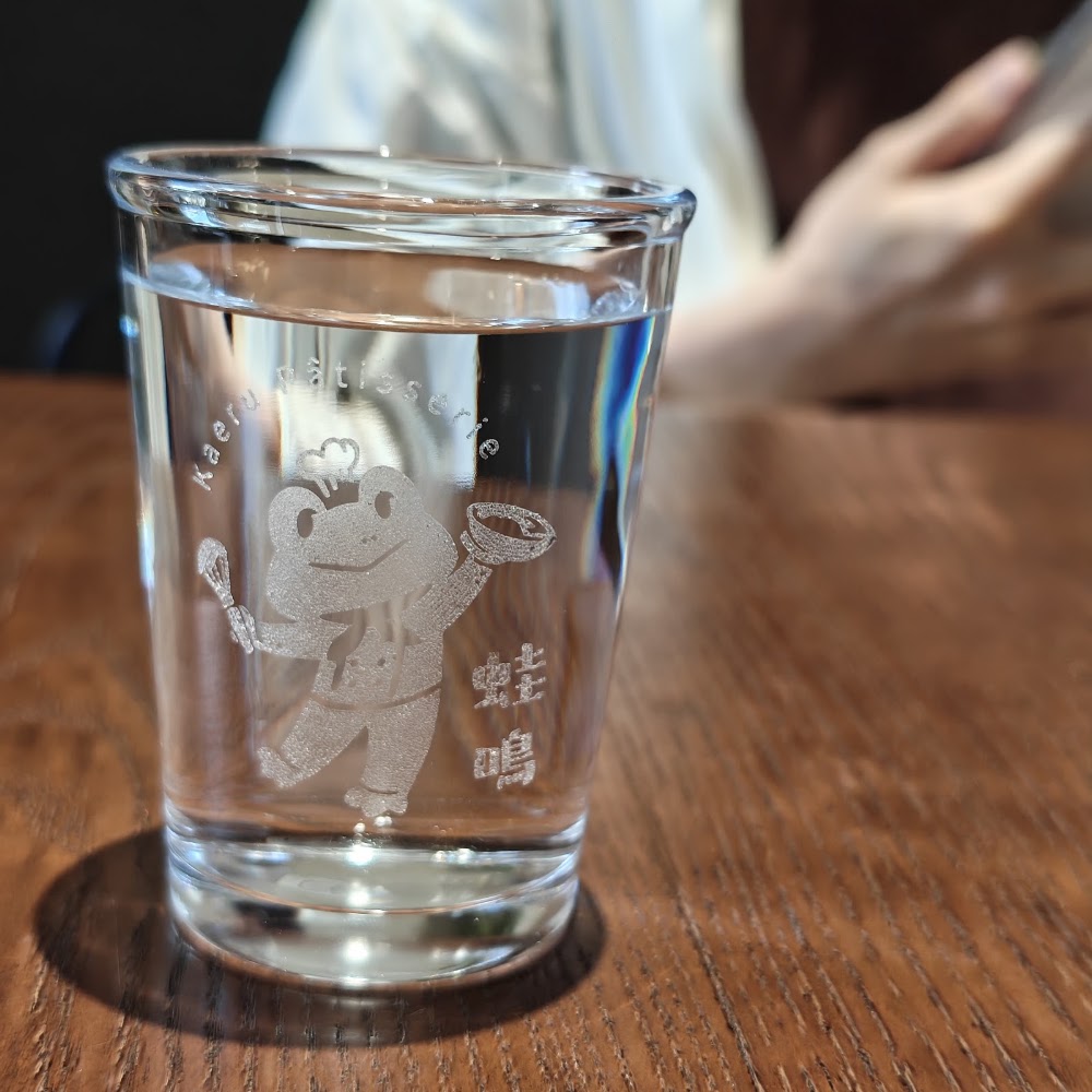 印有青蛙廚師圖案的玻璃水杯，是蛙鳴甜點的可愛細節之一