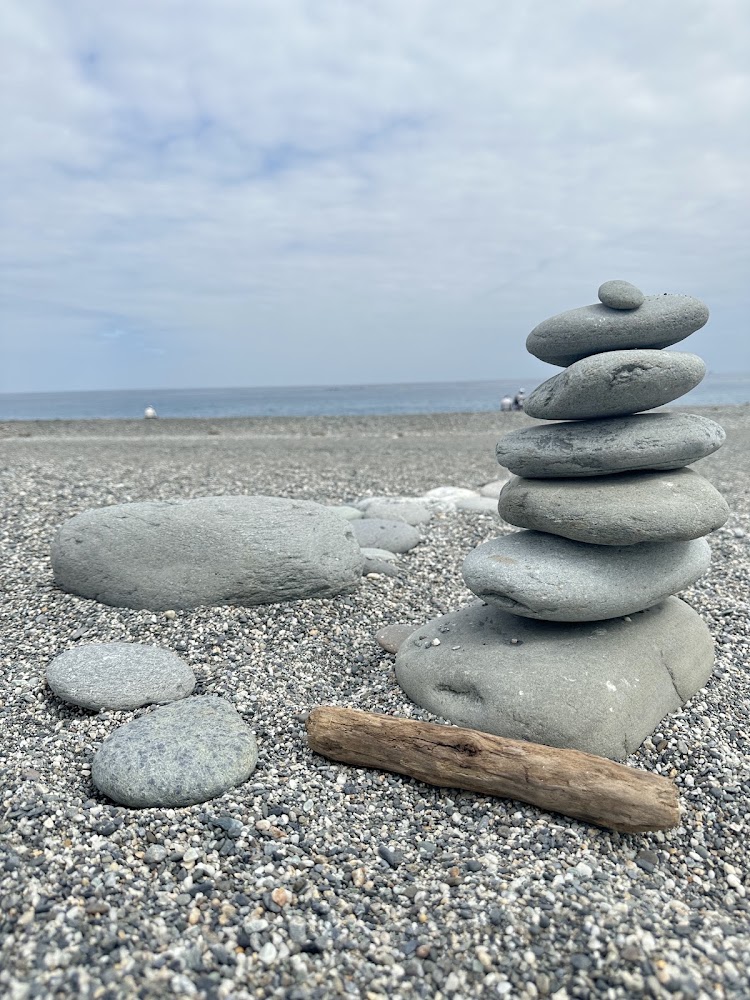 海邊堆疊鵝卵石與漂流木,背景是藍天大海