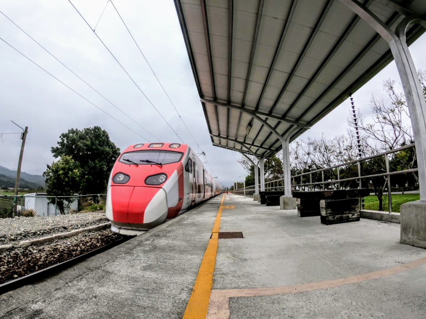 紅白塗裝電聯車進站,瑞和車站月台雨棚與鐵軌延伸畫面
