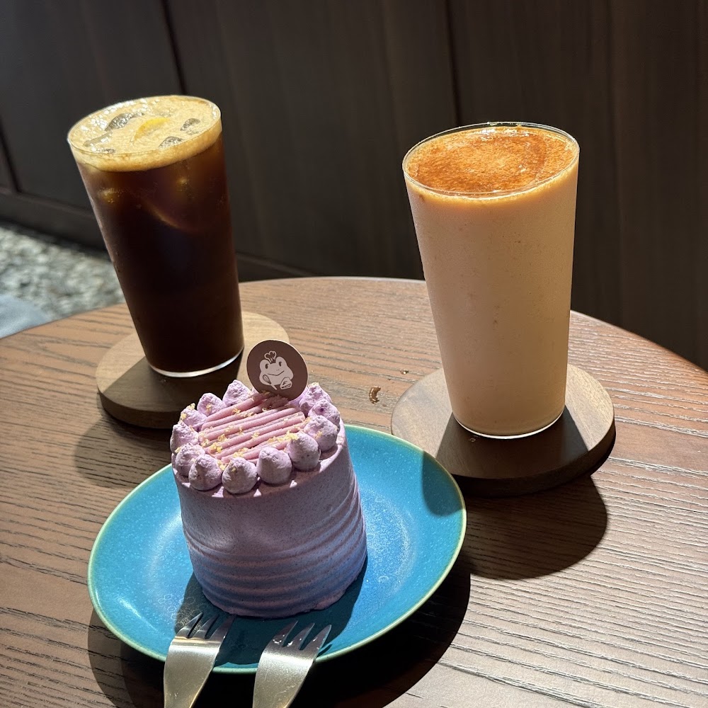 木桌上有兩杯飲料和一個紫色小蛋糕，整體相當精緻