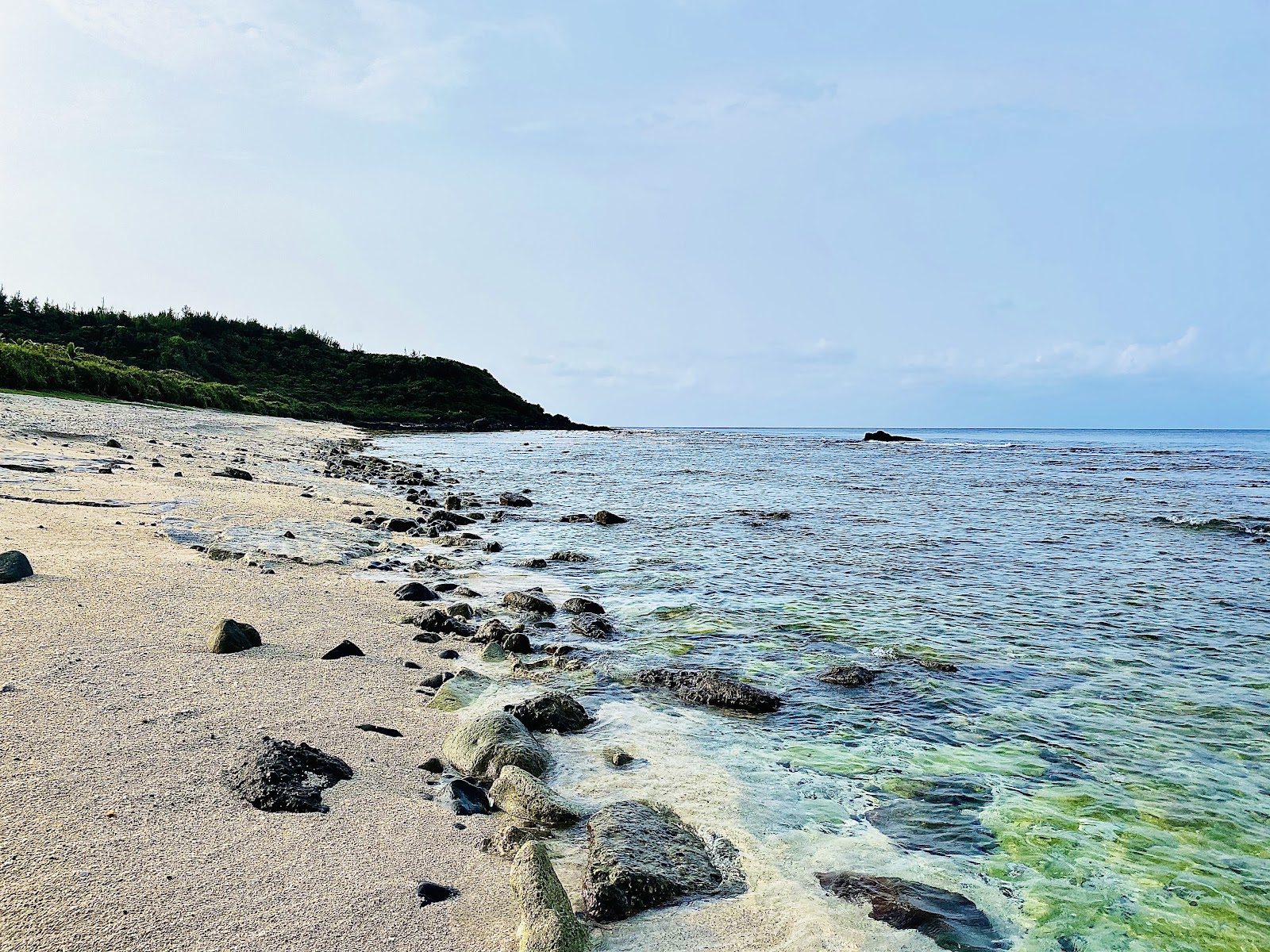 大白沙沙灘邊緣礁石清澈綠藍海水山丘背景綠島