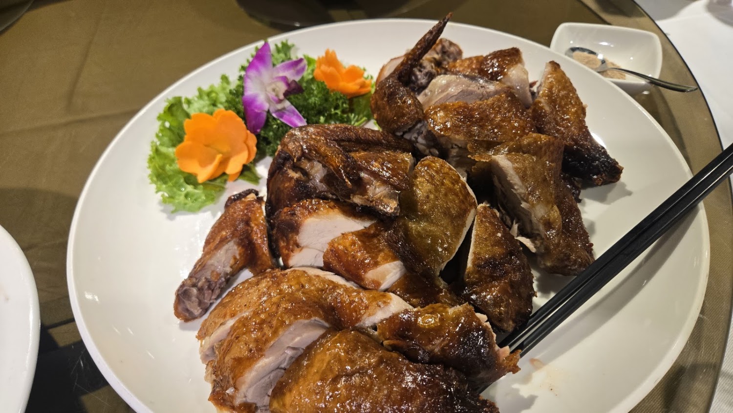 切片烤雞外皮金黃酥脆,旁邊有生菜與裝飾花