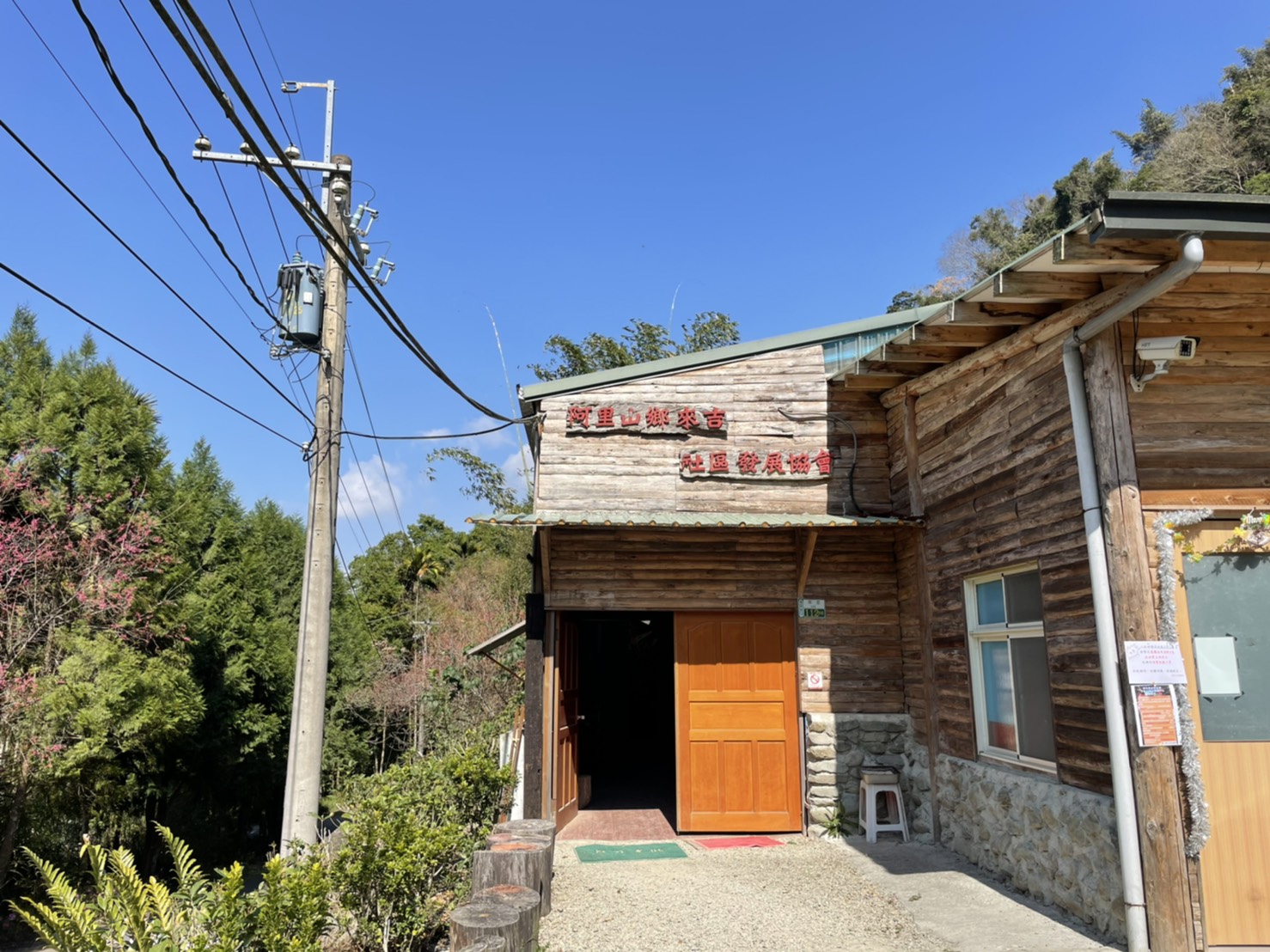 來吉社區發展協會暨山豬工作坊木造建築外觀,藍天下的紅色招牌
