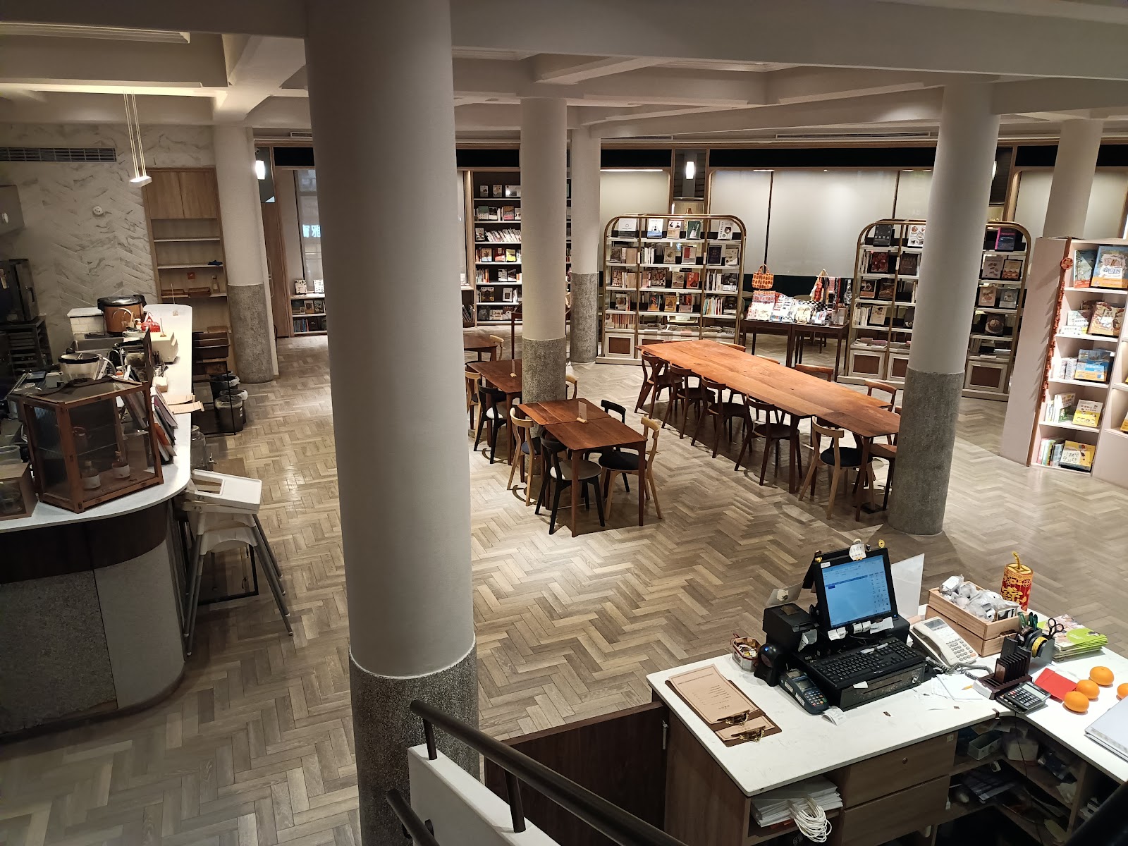 中央書局室內寬敞挑高空間,長型木質閱讀桌、白色圓柱、環繞書架,台中文青書店