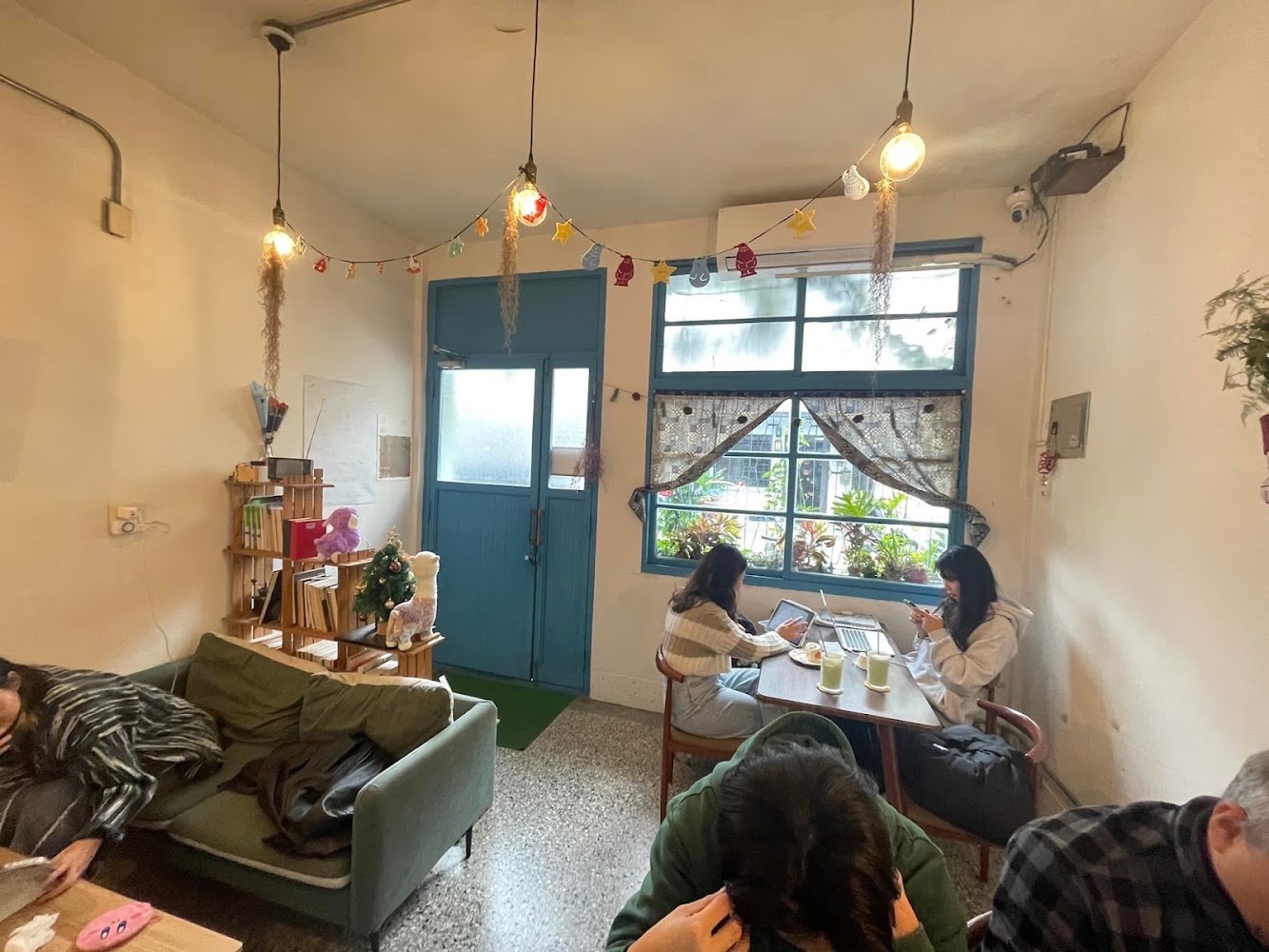 有沙發桌椅書架與燈串的安靜咖啡館內部