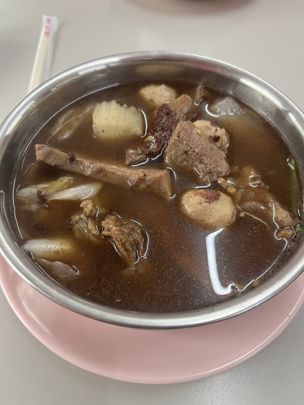 小鳳泰式料理酸辣湯品，不鏽鋼湯碗盛裝肉塊與冬粉