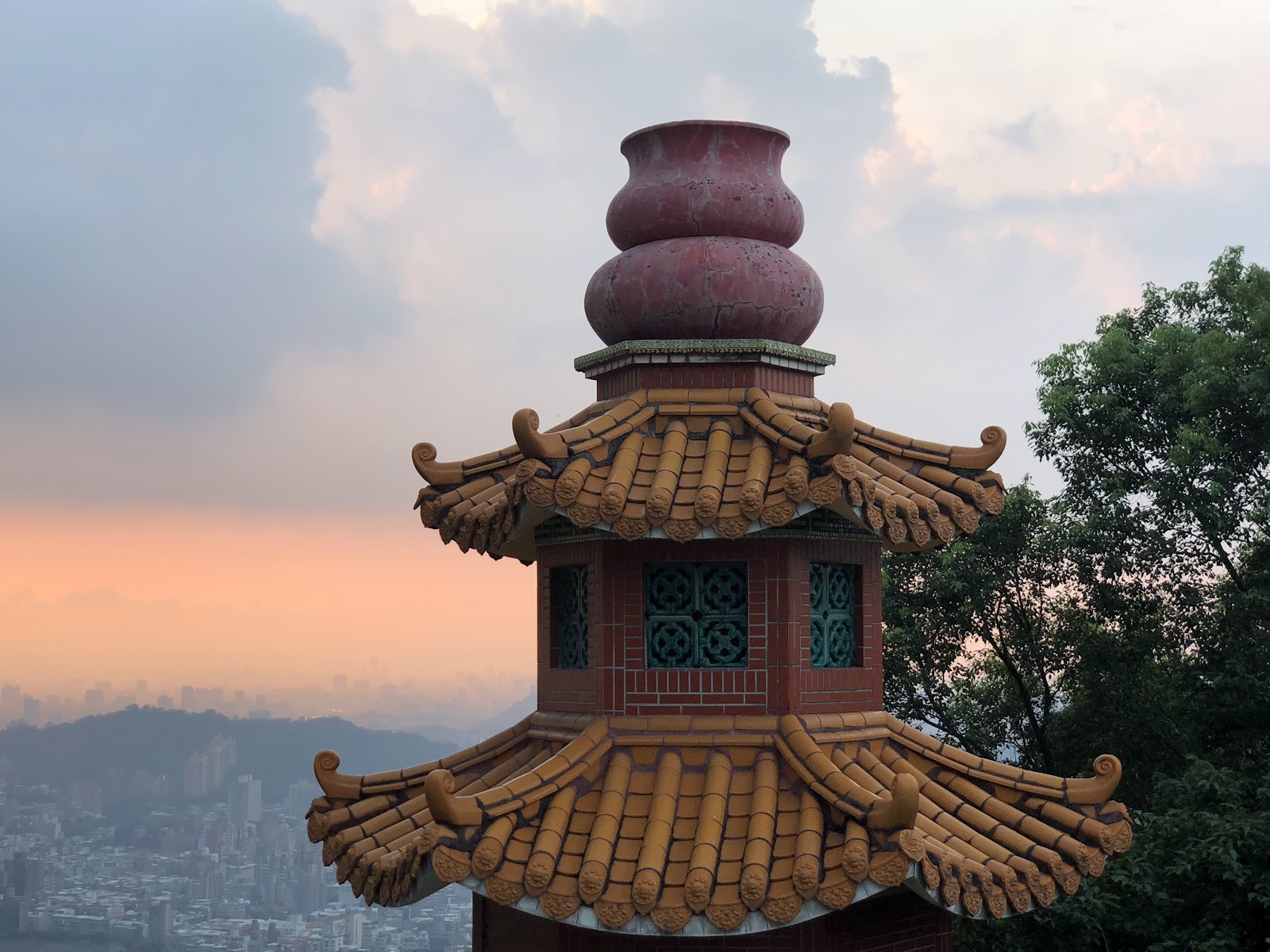 樟山寺塔樓於夕陽下呈現金黃色澤，背景可見台北盆地山巒