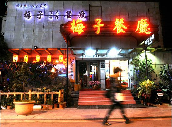 梅子餐廳正面照,門口有紅色霓虹招牌、植物與燈籠